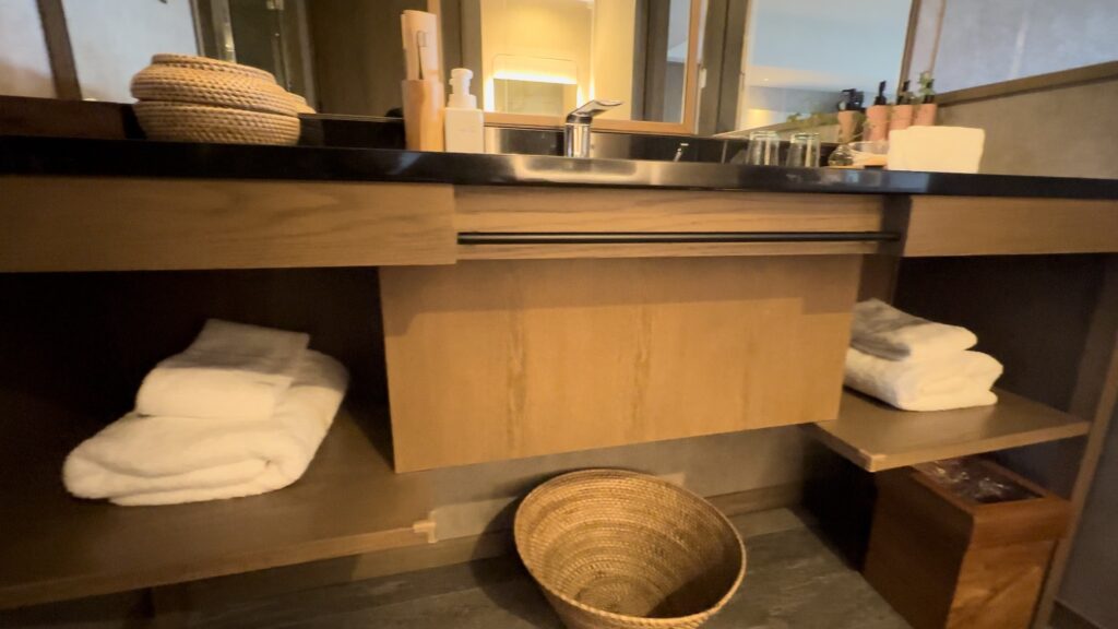 グランディスタイル沖縄読谷ホテル＆リゾートのデラックスセミスイートツインの洗面台の下にタオルが収納されている